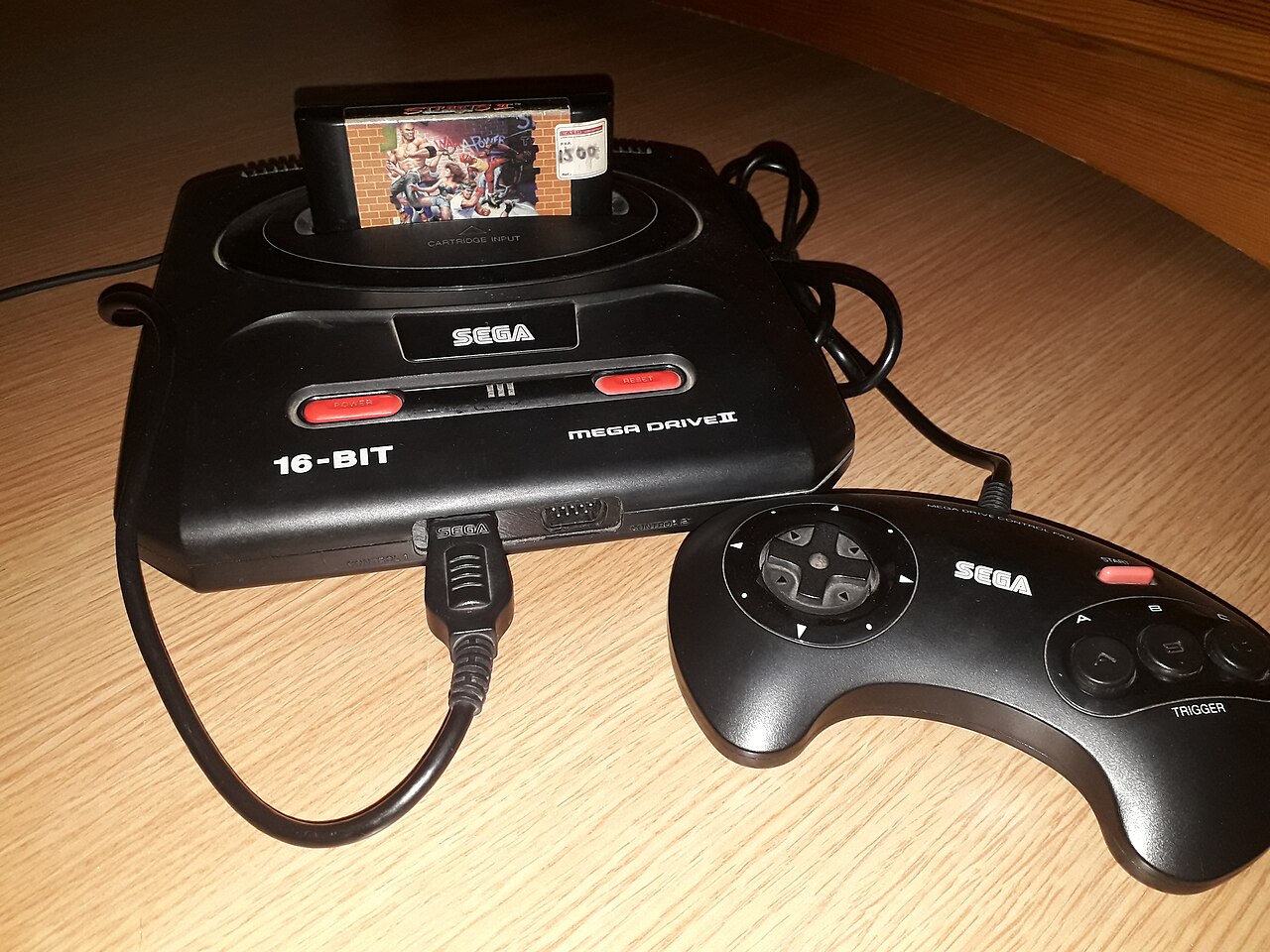 Streets of Rage 2 cartridge inserted in a Sega Mega Drive II beside a controller